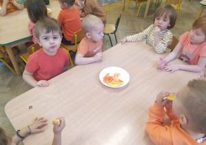 Dzieci próbuja pomarańczowe owoce i warzywa